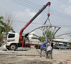 ผลงานในภาพเป็นงานยกและติดตั้งโครงสร้างเหล็กทรงโค้งสำหรับทำหลังคาหรือซุ้มโครงสร้างหน้าอาคารในพื้นที่ตำบลคลองกิ่ว อำเภอบ้านบึง จั